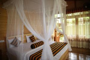 a bedroom with a canopy bed with white curtains at Eco Village in Ella