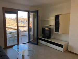 a living room with a tv and a glass table at Appartamento La Croma in Grado