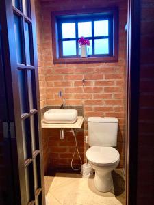 een badkamer met toilet, wastafel en raam bij Abrigo de montanha - Berghütte in São Bento do Sapucaí