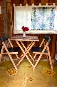 een houten tafel met 2 stoelen en een tafel met bloemen bij Abrigo de montanha - Berghütte in São Bento do Sapucaí +12 foto's