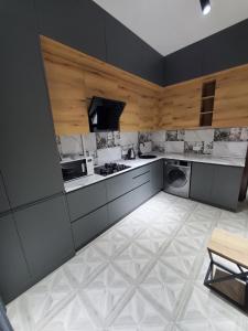 een keuken met grijze kasten en een witte tegelvloer bij Apartment Vokzal 2 in Samarkand