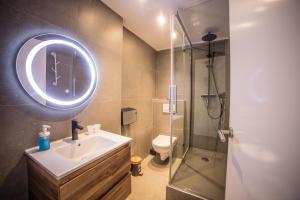 a bathroom with a sink and a glass shower at Hotel Le Provencal in Sluis