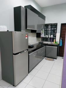 a kitchen with stainless steel appliances and gray cabinets at Pelangi homestay in Kampung Bota Kiri