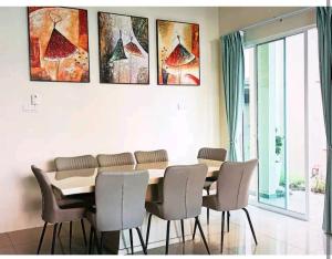 a dining room table with chairs and paintings on the wall at GUESTHOUSE #1 SEMI Bungalow House in Kuah