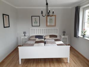 a white bedroom with a large bed with two tables at Appartement Waldfriede in Keutschach am See +35 photos