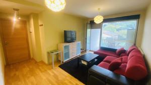 a living room with a red couch and a television at Acogedor apartamento en Llanes in Parres de Llanes