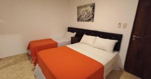 1 dormitorio con 2 camas de color naranja y blanco en Ayres del Rio en Formosa