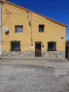 un edificio giallo con finestre sbarrate e una porta di Casa Valeriana Guijosa a Guijosa