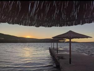 a beach with umbrellas and the ocean at sunset at Apartman Mia Mare in Kraj +10 photos