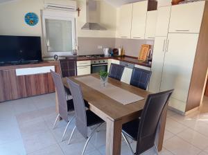a kitchen with a wooden table and gray chairs at Apartman Mia Mare in Kraj