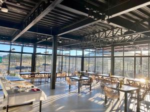 uma sala de jantar com mesas, cadeiras e janelas em Xaroma em Valle de Guadalupe