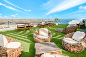 a patio with wicker chairs and tables and the ocean at Bristol Sunset Beach - Holiday Apartments in Corralejo