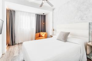 biała sypialnia z łóżkiem i pomarańczowym krzesłem w obiekcie Bristol Sunset Beach - Holiday Apartments w Corralejo