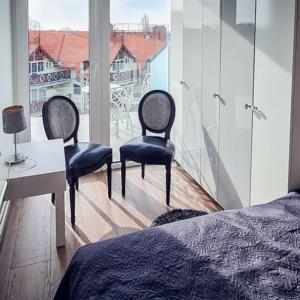 een slaapkamer met 2 stoelen, een tafel en een raam bij Lelle Marine Resort Voila Apartman in Balatonlelle