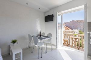 a dining room with a table and chairs and a balcony at Apartment Anna - 20 m from the sea in Postira