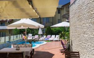 a patio with tables and umbrellas next to a pool at Vila Vista Вила Виста in Sveti Vlas