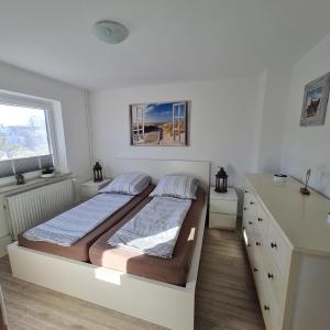 a white bedroom with a bed and a dresser at Wohnung "Orther Hafen" in Bannesdorf auf Fehmarn in Fehmarn