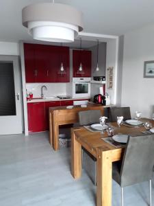 uma cozinha com uma mesa de madeira e armários vermelhos em Les balcons du lac em Malbuisson