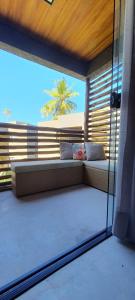 a balcony with a couch and a view of a palm tree at Praia do Patacho - Milagres in Pôrto de Pedras