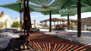 a patio with green umbrellas and couches at Bedouin Valley Eco Resort in Marsa Alam City