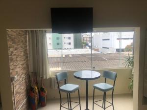 mesa y sillas en una habitación con ventana en Lindo APARTAMENTO com Varanda à 100m - Praia de BOA VIAGEM, en Recife