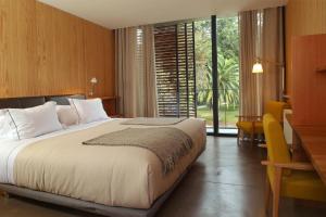 a bedroom with a large bed and a large window at Las Majadas Hotel & Centro de Reuniones in Pirque