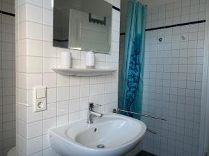 a white bathroom with a sink and a mirror at Ferienhaus Lütt Hüsken in Lemgo