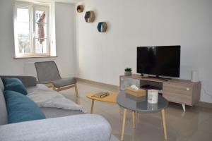 uma sala de estar com um sofá e uma televisão em Maison rénovée au calme em Dannevoux