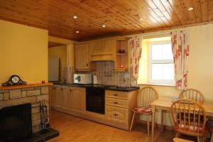 a kitchen with wooden cabinets and a table and a fireplace at John Joe's Self Catering in Blacklion