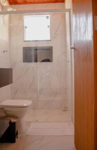 um banheiro com chuveiro, vaso sanitário e janela em Chalés Vale do Sossego em Monte Verde mais 24 fotografias