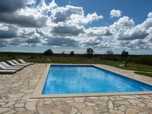 una piscina con sillas y un cielo con nubes en At Home In Istria- Villa Stancia Cicada, en Žminj