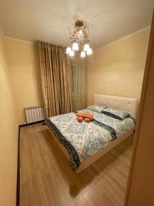 Schlafzimmer mit einem Bett und einem Kronleuchter in der Unterkunft AK-BULAK TOWN Apart in Astana
