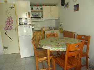 La cuisine est équipée d'une table, de chaises et d'un réfrigérateur blanc. dans l'établissement Résidence Hameau du Soleil, à Valras-Plage