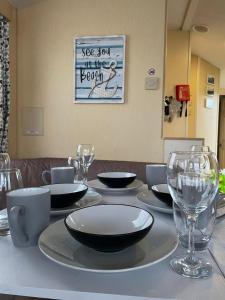 una mesa con platos y copas de vino. en 54 Family Caravan at Marine Holiday Park, sleeps 4, en Rhyl
