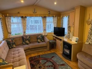 a living room with a couch and a tv at 54 Family Caravan at Marine Holiday Park, sleeps 4 in Rhyl