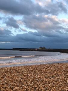 a beach with a cloudy sky and the ocean w obiekcie Quirky Lyme Regis Apartment Near Beach w mieście Lyme Regis