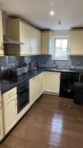 una cocina con armarios blancos y electrodomésticos negros en Two Bedroom Flat Town Centre Colchester, en Colchester