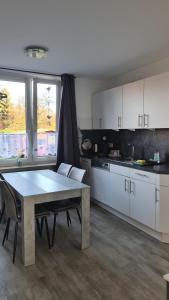 a kitchen with white cabinets and a table and chairs at Ferienhaus Femke in Emden