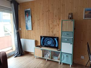 a living room with a television and a cabinet at Les Obiones, vue latérale mer, Fort Mahon Plage, magnifique studio cabine 4p, avec balcon , parking privé gratuit, wifi, classé 2 étoiles, exposition plein sud en Baie de Somme in Fort-Mahon-Plage