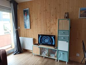 a living room with a television and a cabinet at Les Obiones, Fort Mahon Plage, magnifique studio cabine 4p vue latérale mer avec balcon , parking privé gratuit, wifi, classé 2 étoiles, exposition plein sud en Baie de Somme in Fort-Mahon-Plage