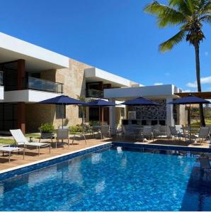 a swimming pool with chairs and umbrellas next to a house at Pé na areia Itacimirim in Camacari