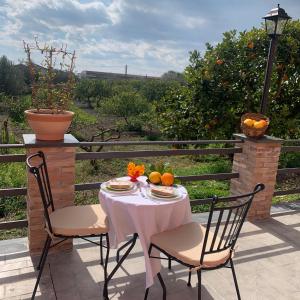 uma mesa com duas cadeiras e laranjas num pátio em La Pomelia B&b Sofia em Trappitello