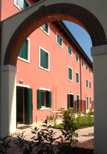 un bâtiment rouge avec une arche devant lui dans l'établissement B&B Corte dei Cedri, à Bussolengo