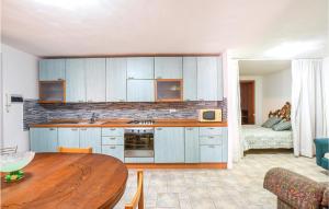 een keuken met blauwe kasten en een tafel in een kamer bij Beautiful Apartment In La Ciaccia With House Sea View in Codaruina