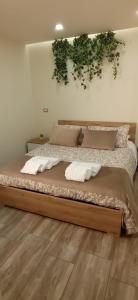 1 dormitorio con 1 cama grande con plantas en la pared en I Mori APARTAMENT, en Ragalna