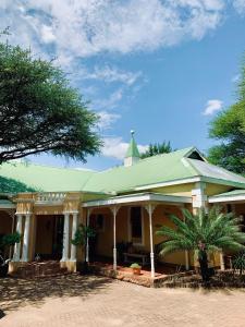 a house with a green roof and a palm tree at Ngangane Lodge & Reserve in Francistown