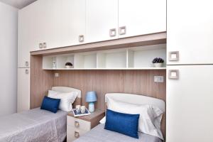 2 bedden in een kleine kamer met blauwe kussens bij Residence Chiaro di Luna in San Teodoro