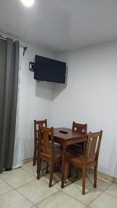 mesa de madera con sillas y TV en la pared en Hospedaje Rio Celeste Katira, Habitación privada, en San Rafael