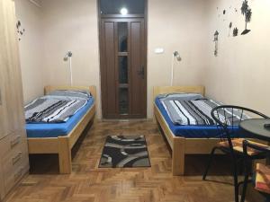 ハイドゥソボスローにあるTahiti Apartmanのベッド2台、テーブル、ドアが備わる客室です。