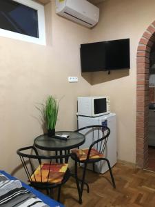 ハイドゥソボスローにあるTahiti Apartmanのテーブル、椅子、テレビが備わる小さな客室です。